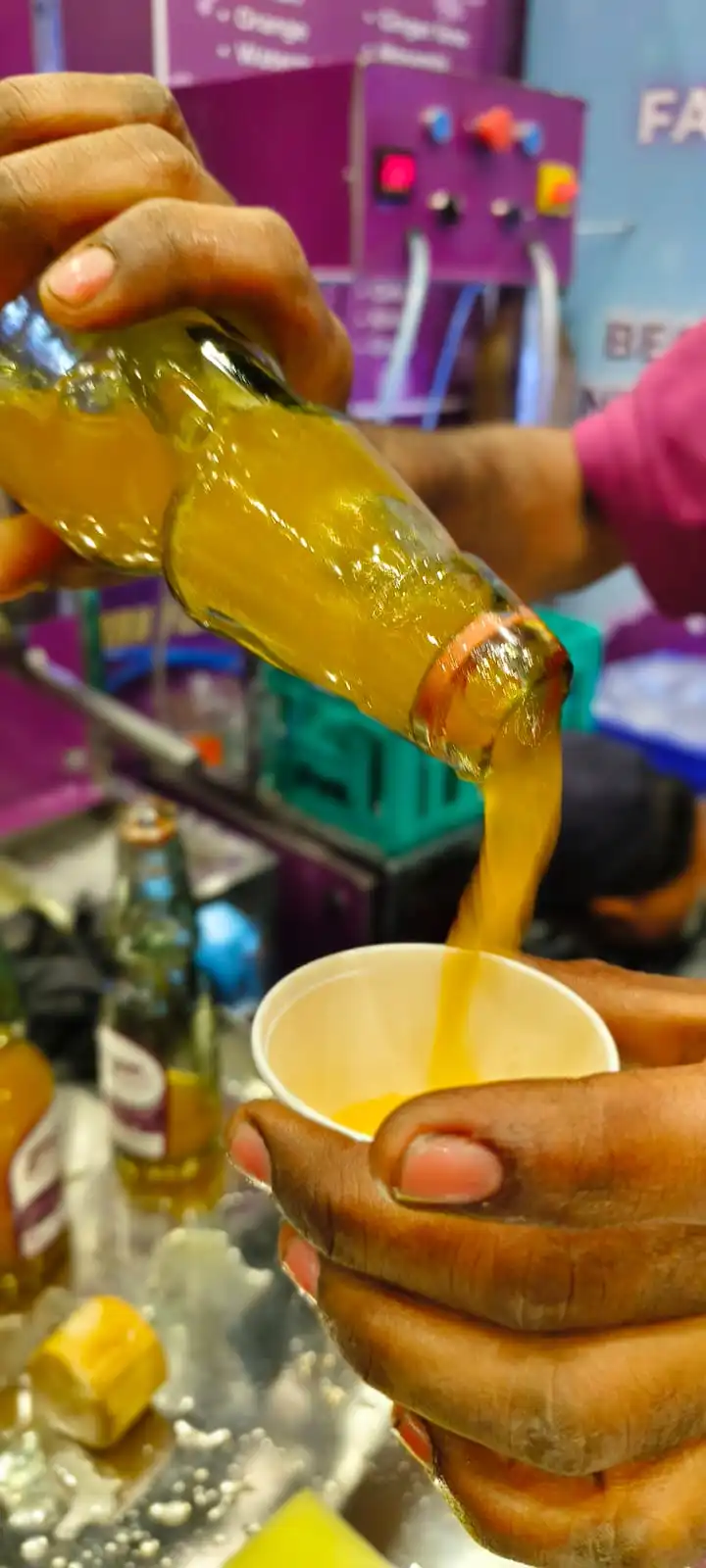 Zingoo Goli Soda Bottle with Mango Flavor pouring soda in a plastic glass