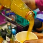 Zingoo Goli Soda Bottle with Mango Flavor pouring soda in a plastic glass